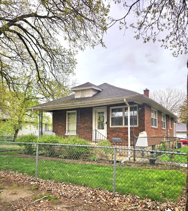 view of front of home with a chimney, a fenced front yard, a front yard, and brick siding