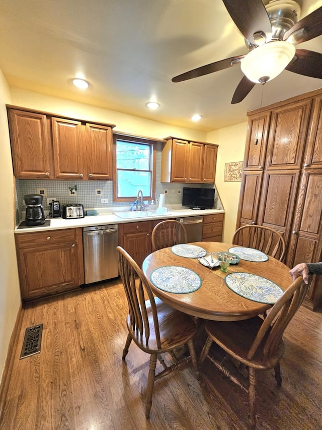 kitchen featuring brown cabinets, dishwasher, light wood-style flooring, tasteful backsplash, and visible vents