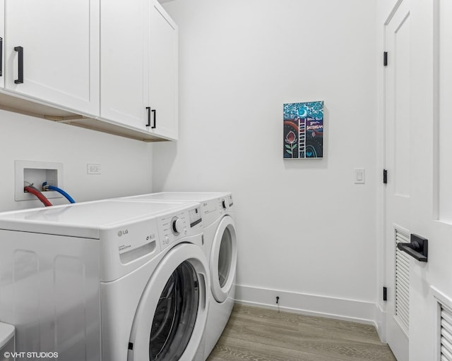 clothes washing area featuring cabinet space, baseboards, washer and clothes dryer, and light wood-type flooring