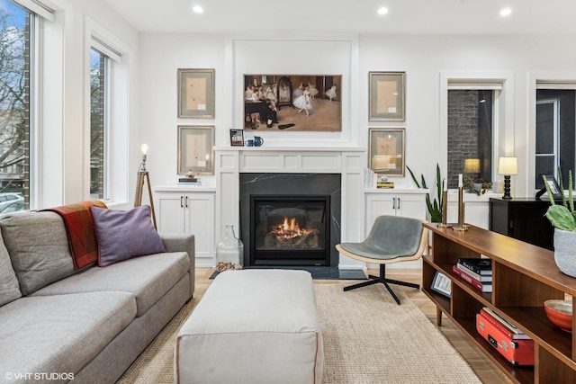 living area featuring recessed lighting, a fireplace with flush hearth, and light wood finished floors