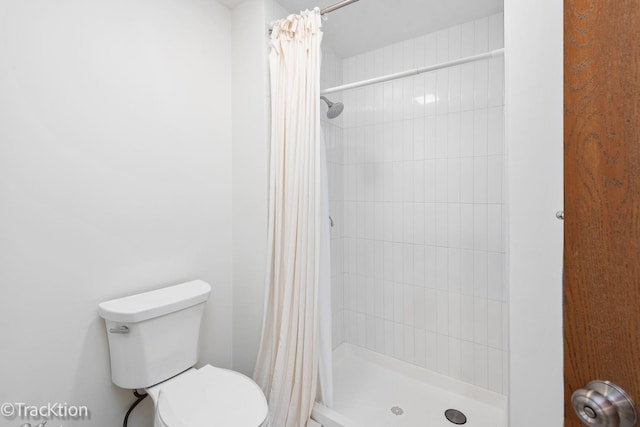 bathroom featuring a shower stall and toilet