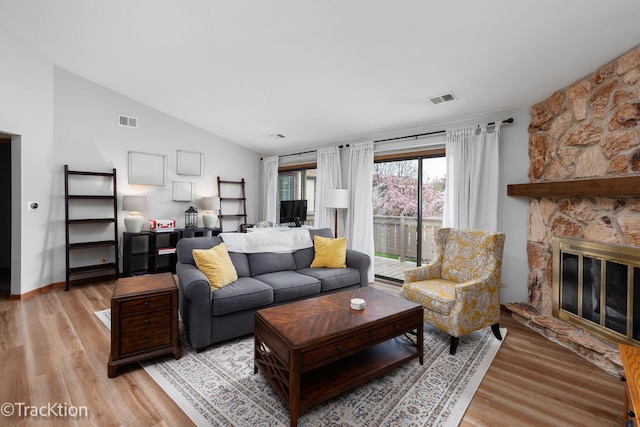 living room featuring visible vents, light wood-style flooring, and lofted ceiling