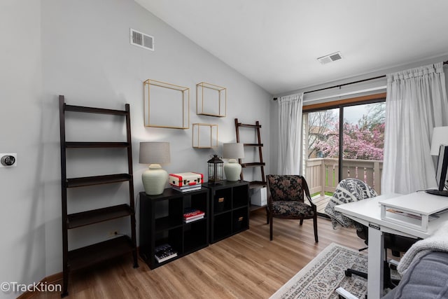 office area featuring visible vents, light wood finished floors, and vaulted ceiling