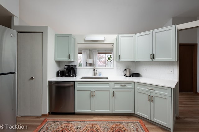 kitchen with a sink, appliances with stainless steel finishes, backsplash, and light countertops