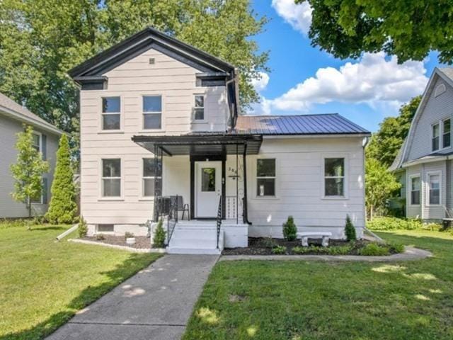 traditional-style house featuring metal roof and a front yard