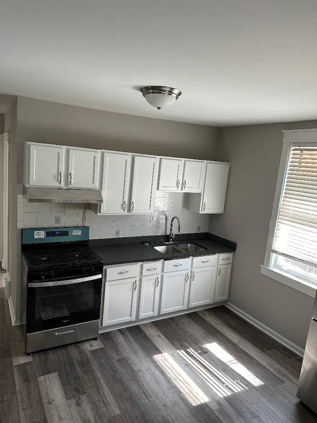kitchen featuring stainless steel gas range oven, dark wood finished floors, a sink, white cabinets, and under cabinet range hood