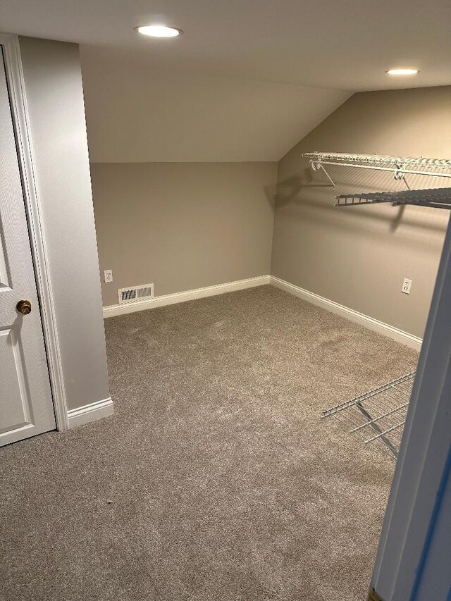 spacious closet featuring visible vents, lofted ceiling, and carpet