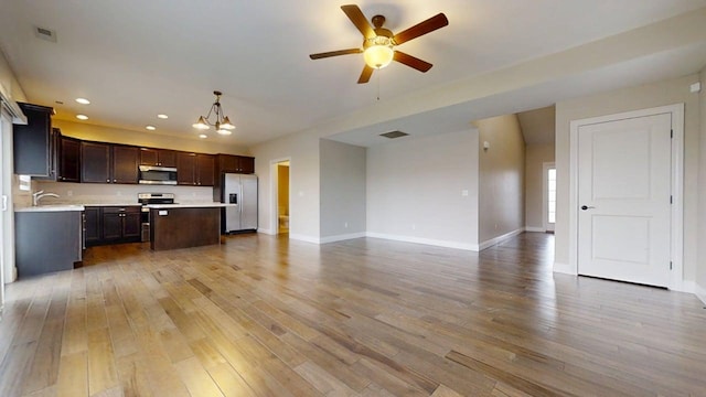 unfurnished living room with visible vents, baseboards, recessed lighting, light wood-type flooring, and ceiling fan with notable chandelier