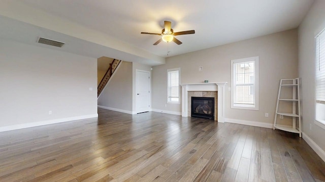unfurnished living room featuring dark wood-style flooring, a fireplace, a ceiling fan, baseboards, and visible vents