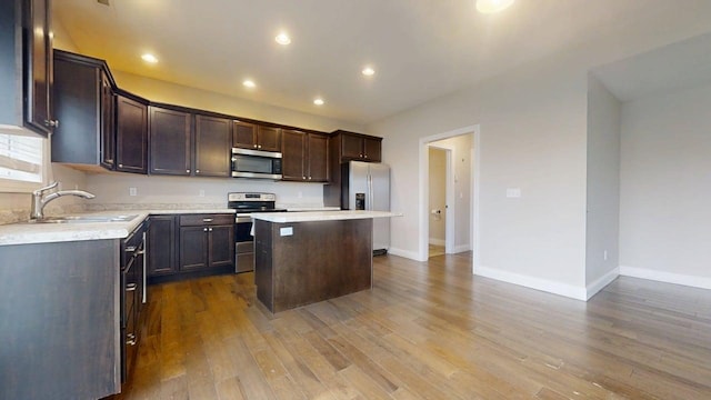 kitchen featuring dark brown cabinetry, appliances with stainless steel finishes, a center island, a sink, and light countertops