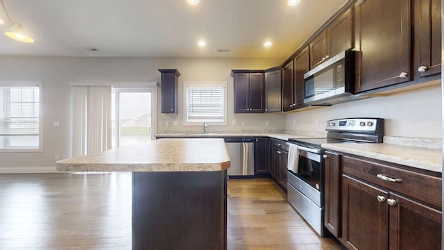 kitchen with light countertops, stainless steel appliances, a sink, and a center island