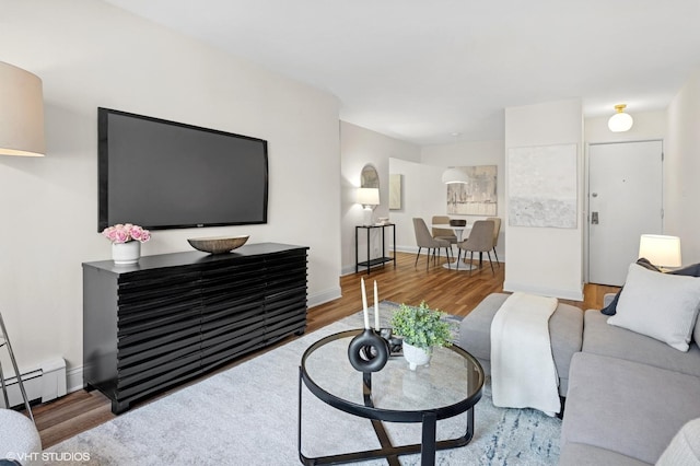 living room with baseboards, a baseboard heating unit, and wood finished floors