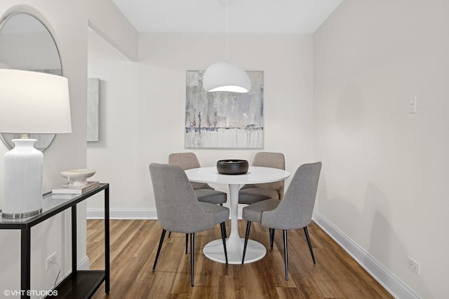 dining space with baseboards and wood finished floors