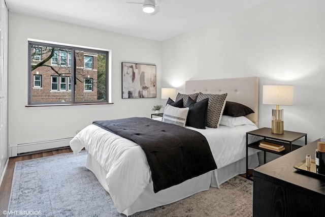 bedroom with wood finished floors and a baseboard heating unit
