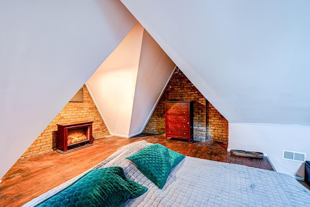 8240 S Champlain Ave, Chicago, IL 60619 - bedroom with visible vents, a brick fireplace, wood finished floors, and vaulted ceiling
