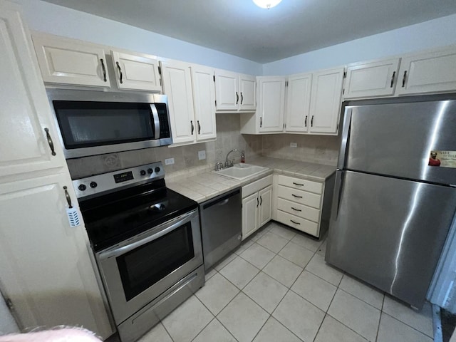 300 Park Ave Unit 443, Calumet City, IL 60409 - kitchen featuring tile countertops, appliances with stainless steel finishes, a sink, light tile patterned floors, and white cabinets