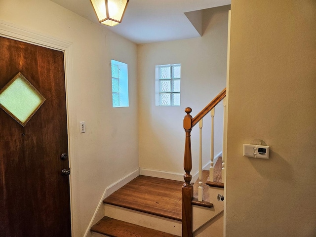 foyer entrance featuring stairway, baseboards, and wood finished floors