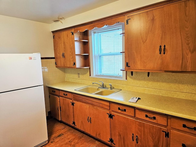 kitchen featuring brown cabinetry, open shelves, a sink, light countertops, and freestanding refrigerator