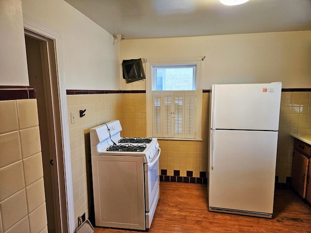 kitchen featuring wainscoting, white appliances, and tile walls