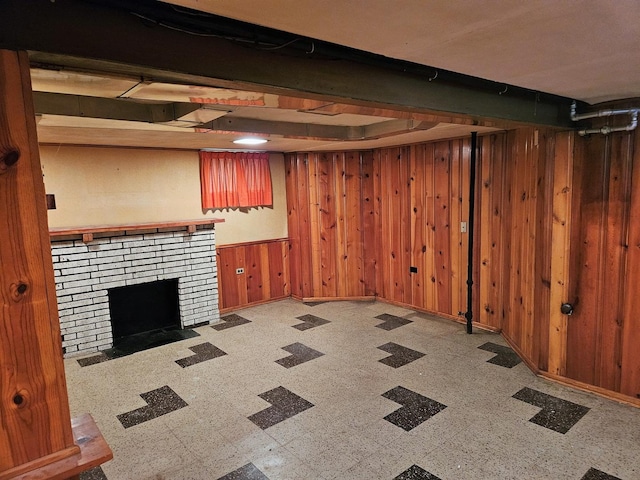 finished below grade area featuring tile patterned floors, baseboards, a fireplace, and wood walls