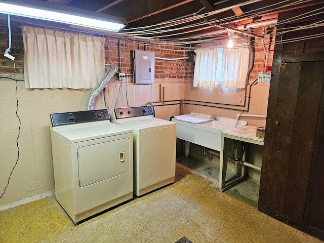 laundry area with a sink, laundry area, washing machine and dryer, and electric panel