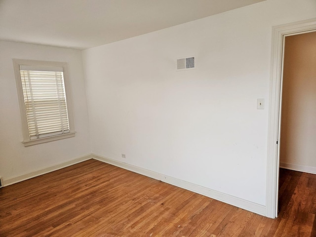 spare room featuring visible vents, baseboards, and wood finished floors