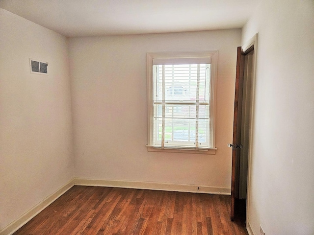 unfurnished room with a healthy amount of sunlight, baseboards, dark wood-style flooring, and visible vents