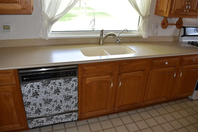 kitchen with brown cabinetry, backsplash, dishwasher, a sink, and light countertops