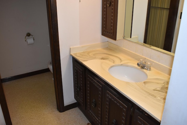 bathroom with vanity, baseboards, and toilet