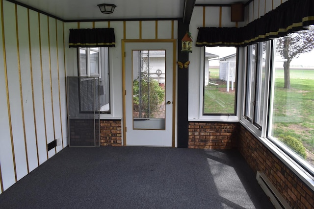unfurnished sunroom featuring carpet floors, brick wall, and baseboard heating