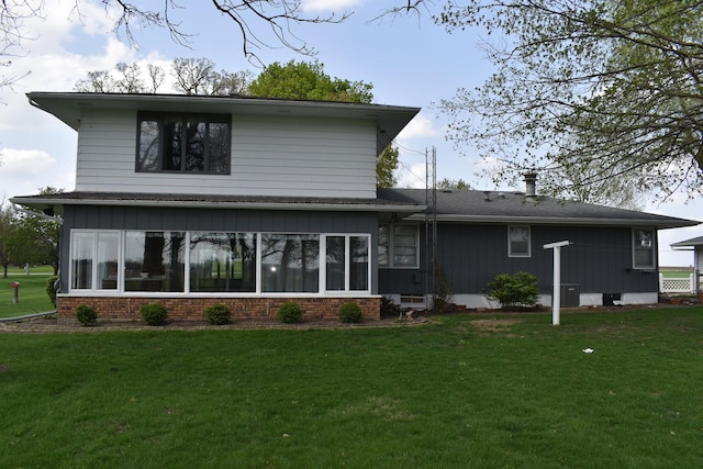 back of house featuring a lawn, brick siding, and central AC unit