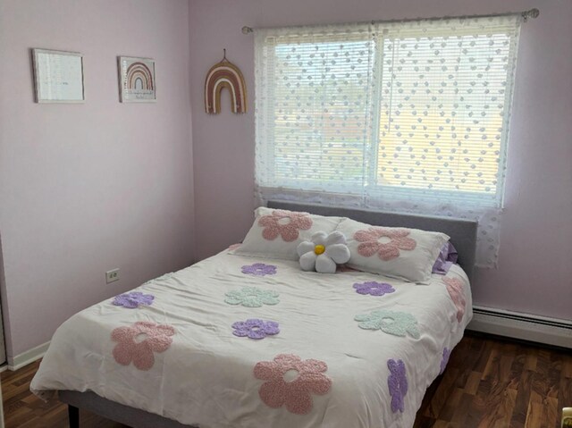 bedroom with baseboards, a baseboard heating unit, and wood finished floors