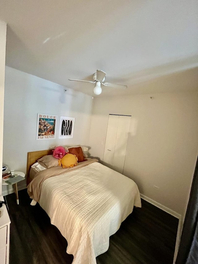 bedroom featuring a ceiling fan, baseboards, dark wood finished floors, and a closet