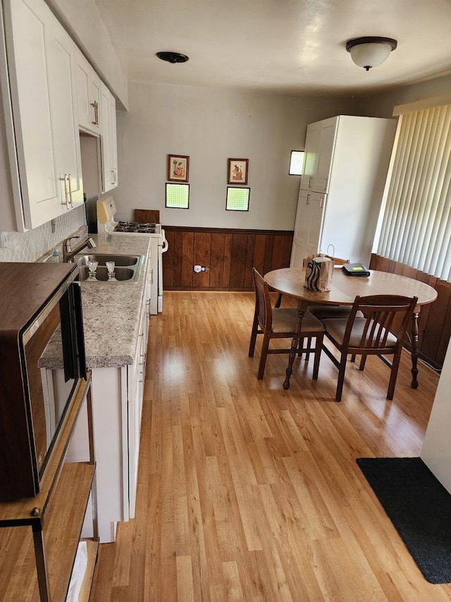 14842 Shepard Dr, Dolton, IL 60419 - kitchen featuring white gas stove, white cabinets, stainless steel microwave, a sink, and light wood-type flooring