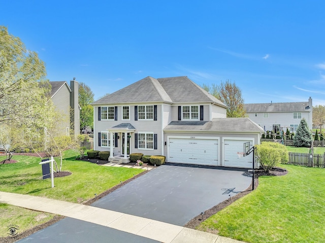 view of front of property featuring an attached garage, fence, a front lawn, and aphalt driveway