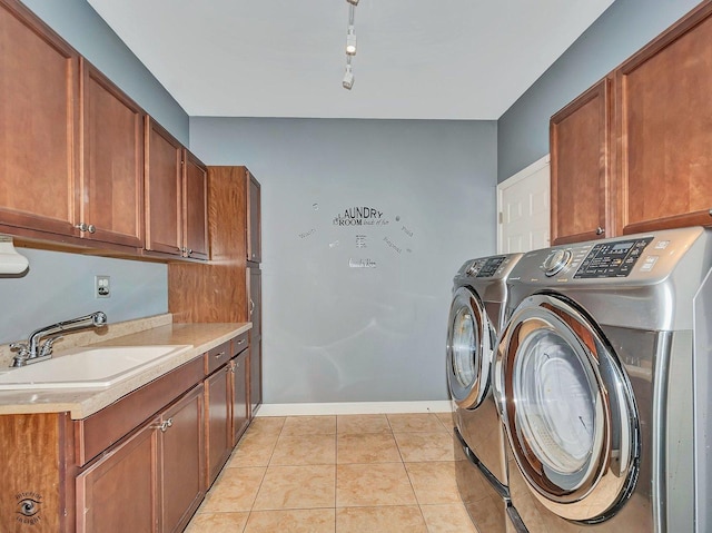 clothes washing area with cabinet space, a sink, separate washer and dryer, baseboards, and light tile patterned floors