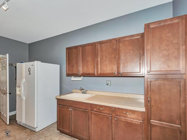 kitchen featuring light countertops, brown cabinets, a sink, and white refrigerator with ice dispenser