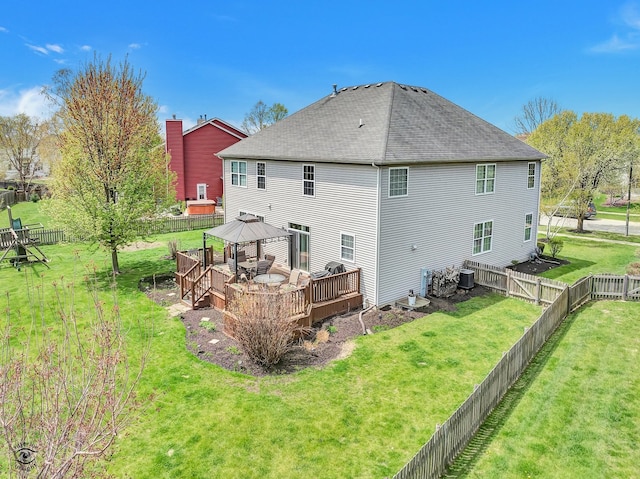 back of house with a shingled roof, a gazebo, a deck, a fenced backyard, and a yard