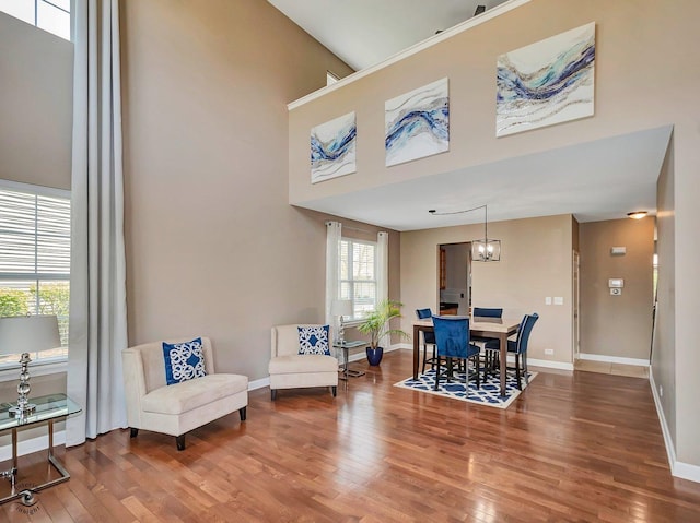 dining space featuring baseboards, a high ceiling, and wood finished floors