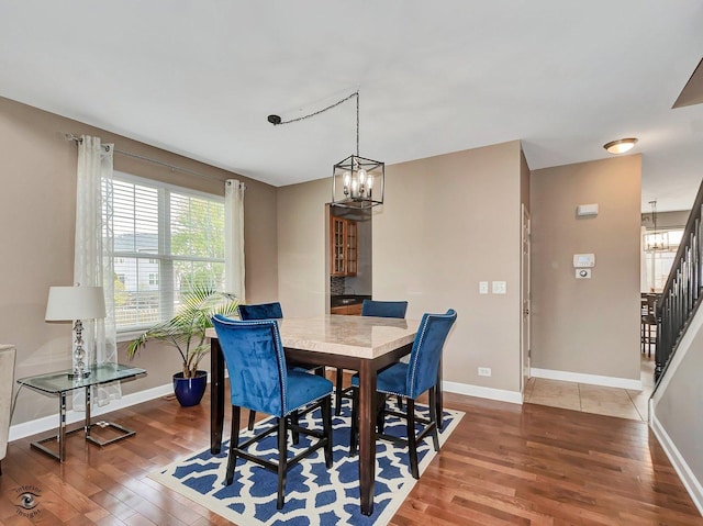 dining area featuring baseboards, stairs, wood finished floors, and a notable chandelier