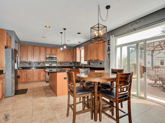 kitchen with decorative backsplash, dark countertops, appliances with stainless steel finishes, a center island, and a sink