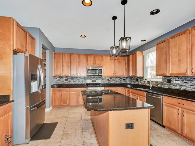 kitchen with appliances with stainless steel finishes, tasteful backsplash, a center island, a sink, and dark stone countertops