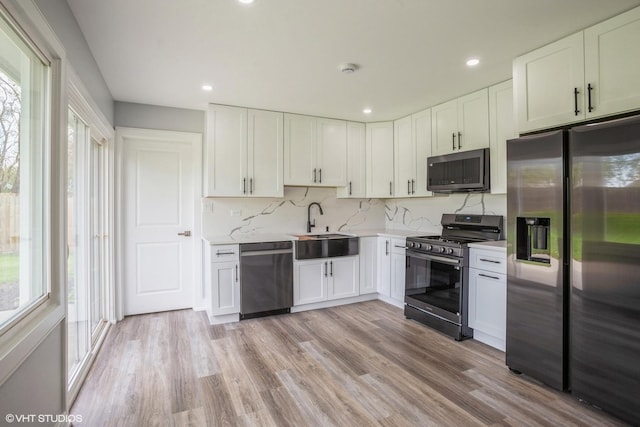 kitchen with light countertops, white cabinetry, tasteful backsplash, a sink, and appliances with stainless steel finishes