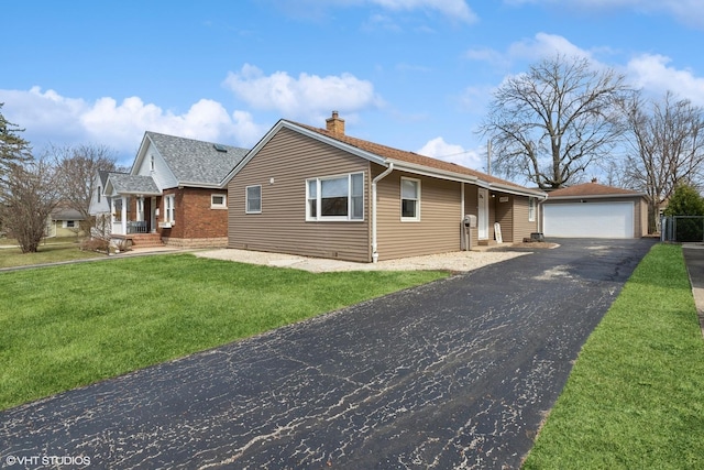 view of front of property featuring a chimney, an outbuilding, a detached garage, a front lawn, and a shingled roof