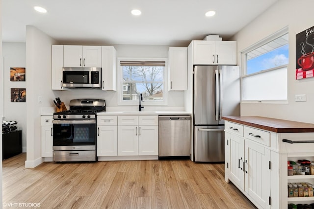 kitchen with a sink, appliances with stainless steel finishes, plenty of natural light, and light wood-style flooring