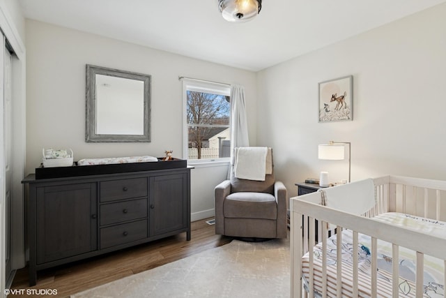 bedroom featuring light wood-style flooring and a nursery area
