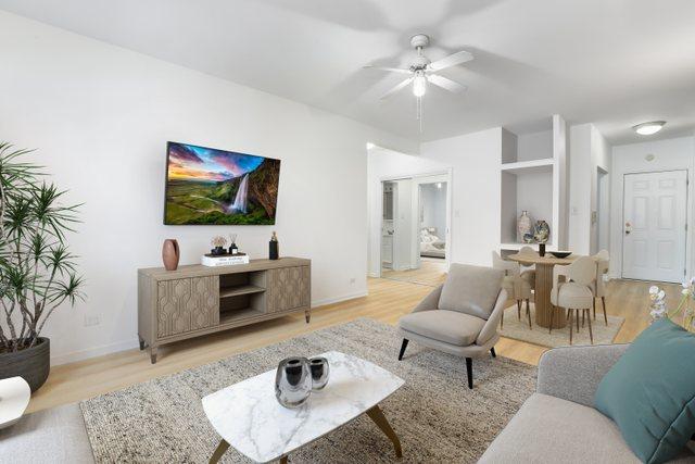 living area featuring baseboards, a ceiling fan, and wood finished floors