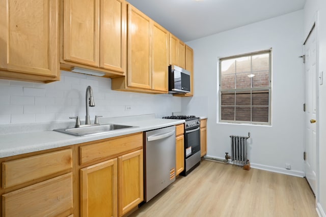 kitchen with dishwasher, a sink, radiator heating unit, range with gas stovetop, and light wood-style flooring