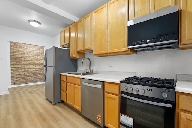 kitchen with light countertops, a sink, light wood-style flooring, and stainless steel appliances