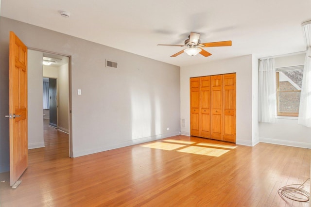 unfurnished bedroom with visible vents, a closet, baseboards, ceiling fan, and light wood-style flooring